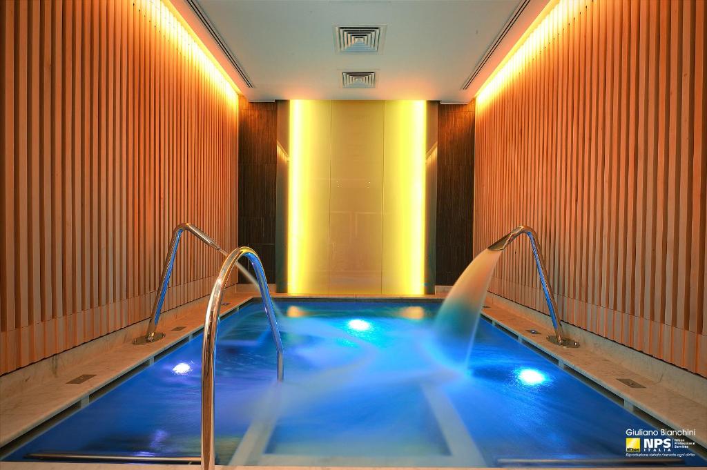 a hot tub with blue water in a room with orange walls at Grand Hotel & Riviera in Lido di Camaiore