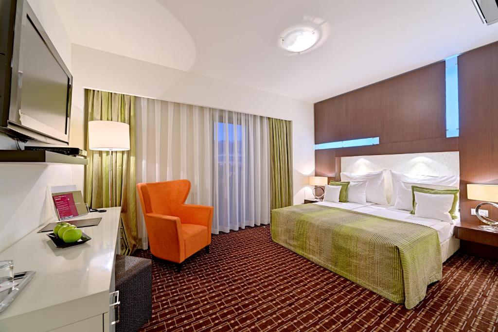 ein Hotelzimmer mit einem Bett und einem Stuhl in der Unterkunft Hotel Cubix in Braşov