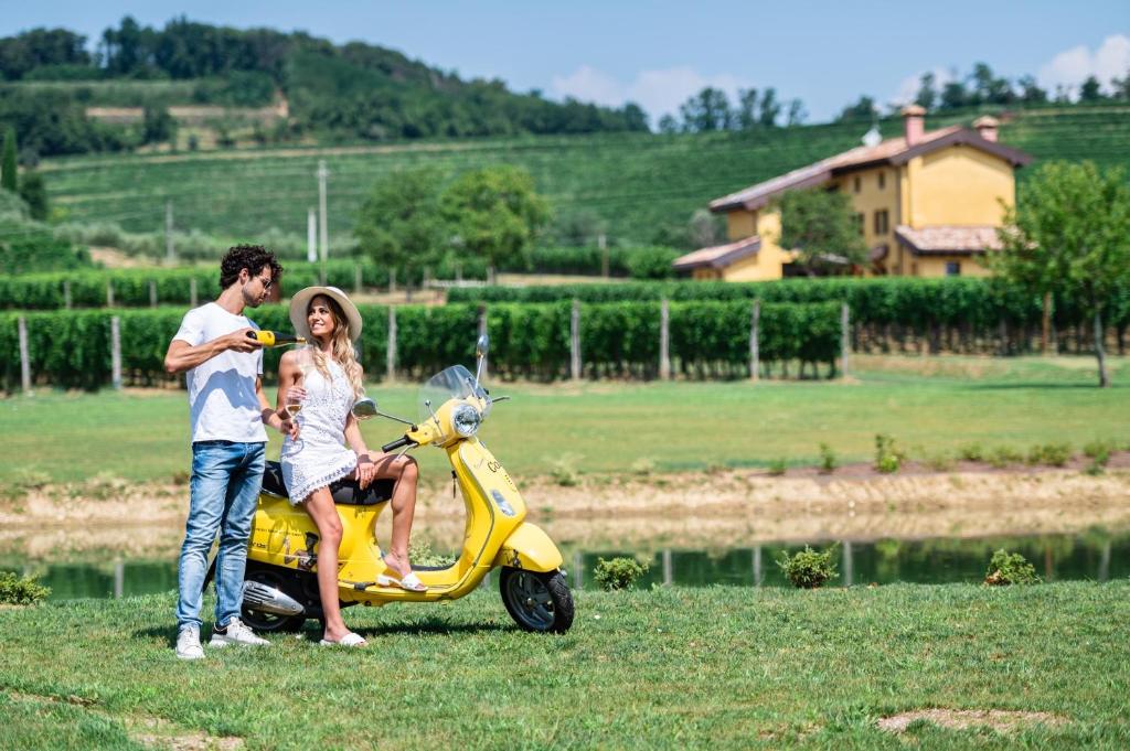 un homme et une femme debout à côté d'un scooter dans l'établissement Al Pompiere - Wine and rooms, à Capriva del Friuli