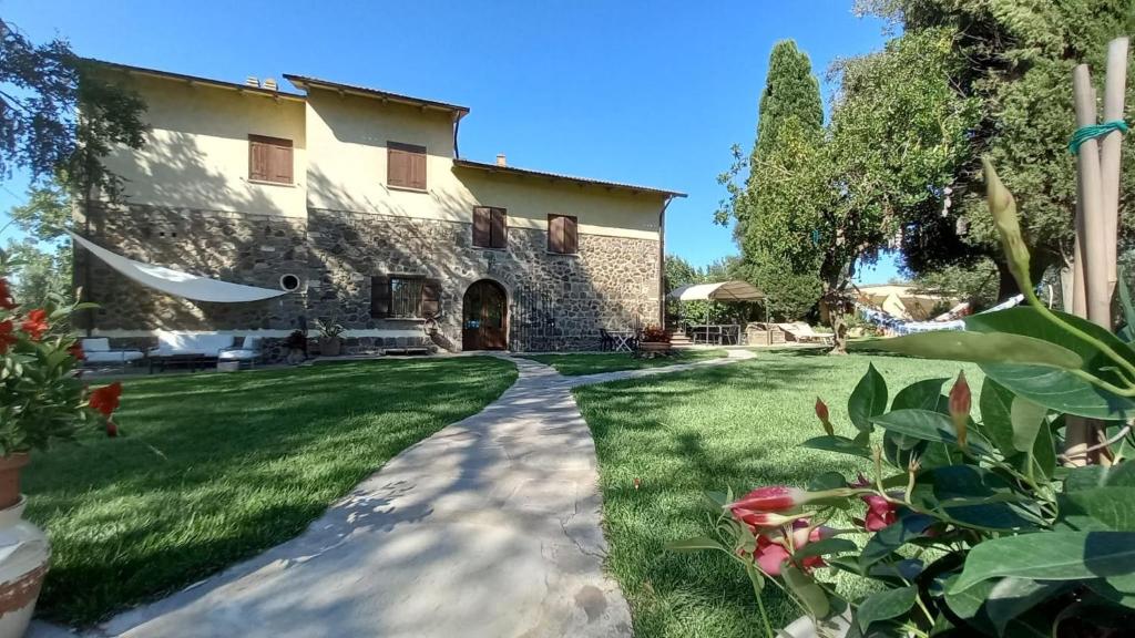 a large stone house with a grass yard at Le Pozze Terme B&B in Viterbo