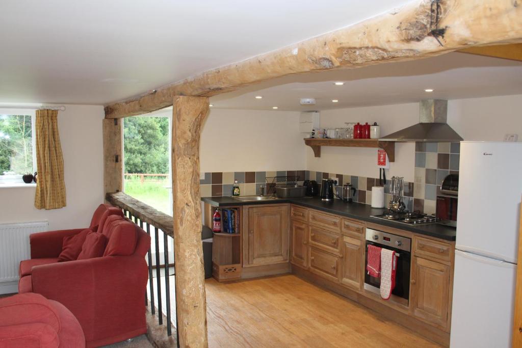 a kitchen with wooden cabinets and a red chair at Little Oaks in Stowmarket