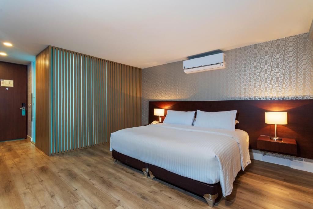 1 dormitorio con 1 cama blanca grande y 2 lámparas en Hotel Santa Barbara Boutique, en Bogotá