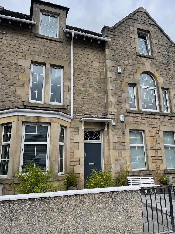 a brick house with a blue door and windows at Premier Apartment C in Broxburn