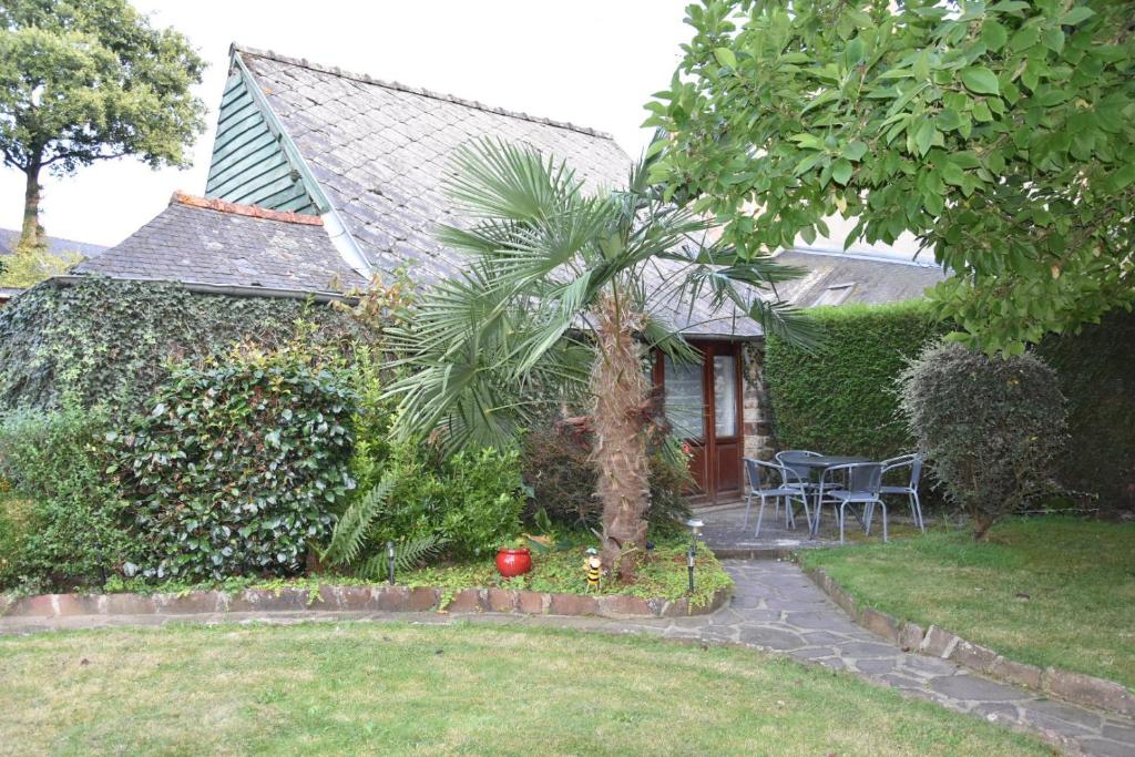 una casa con una palmera en el patio en GITE MAEN ROCH, en Val Couesnon