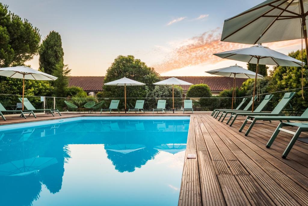 a pool with chairs and umbrellas on a wooden deck at Résidence de Diane - Toulouse in Toulouse