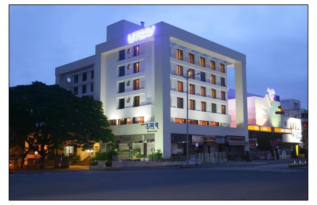 a white building with a sign on top of it at Hotel Utsav Deluxe in Pune