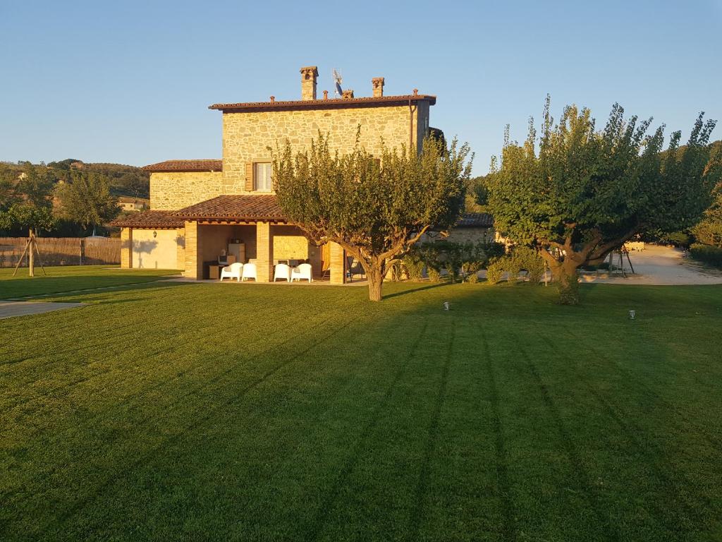 dom z dużym dziedzińcem z drzewami przed nim w obiekcie Agriturismo Villa al piano w mieście Todi