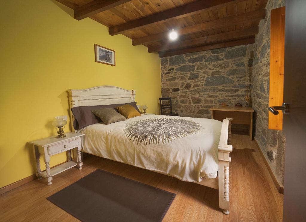 1 dormitorio con cama y pared de piedra en A Casa da Charca - Casa rural con jardín en Pontevedra