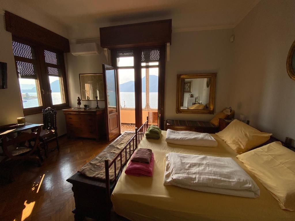 a room with two beds and a desk and windows at Suitecastlelakeview 1 in Bellano