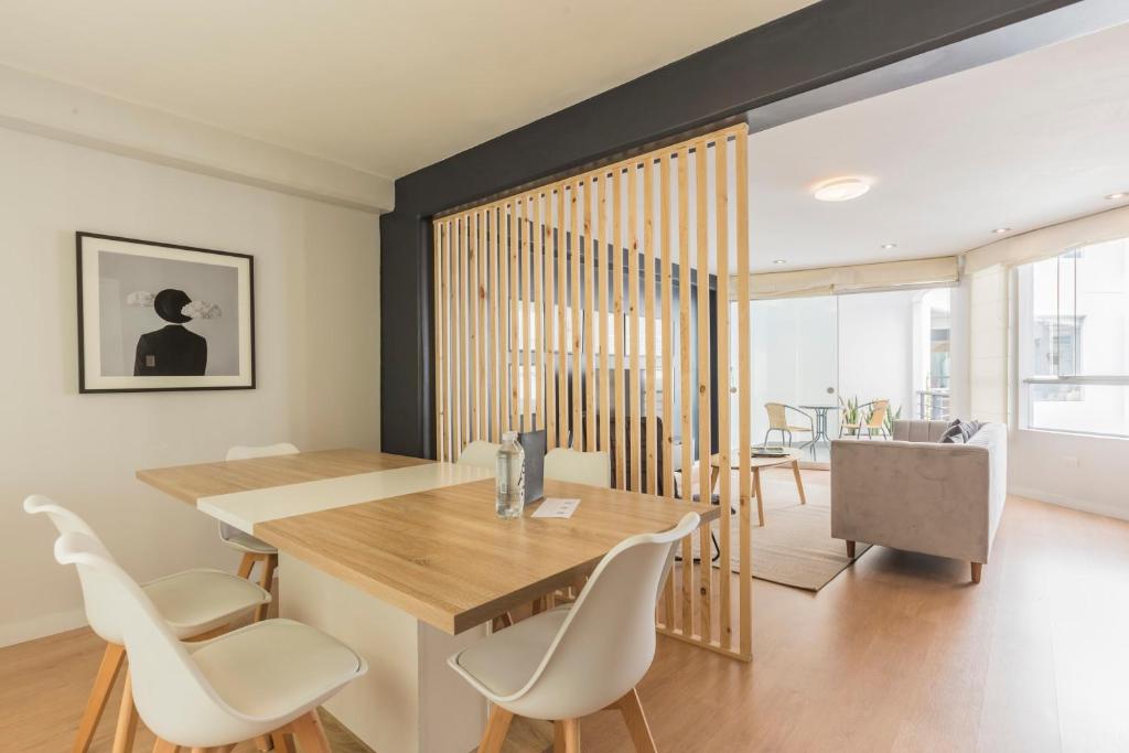 a dining room with a wooden table and white chairs at Natural 3BR in Barranco in Lima