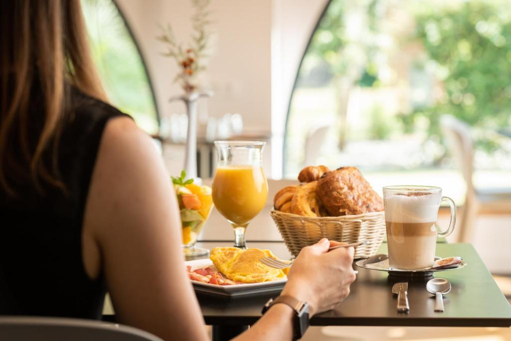 a woman sitting at a table with a plate of food at Résidence de Diane - Toulouse in Toulouse