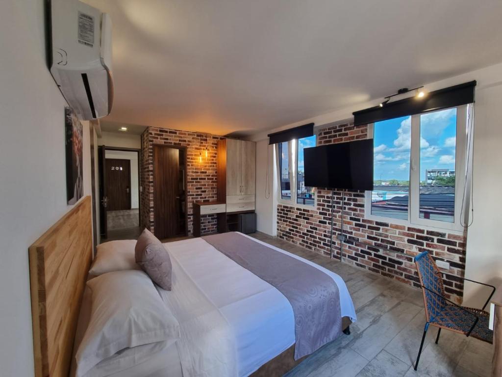 a bedroom with a large bed and a brick wall at Casa del Sol in Villavicencio