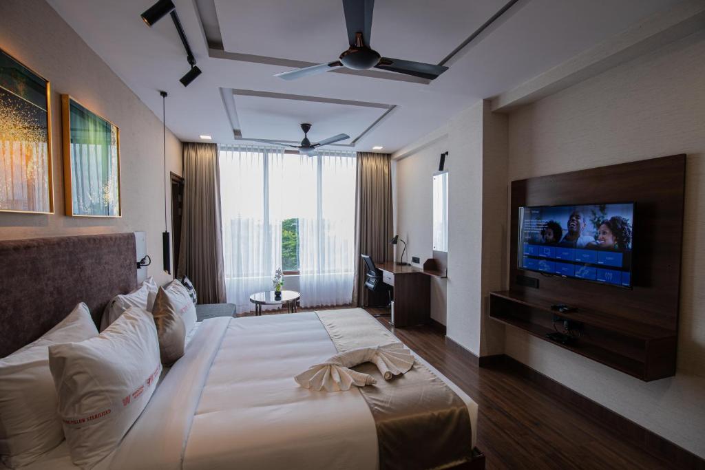 a bedroom with a large bed and a flat screen tv at Windstone Residency in Coimbatore