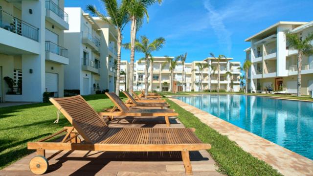 a row of lounge chairs next to a swimming pool at CASABAY Sidi Rahal, appartement avec accés direct à la plage et piscine in Sidi Rahal