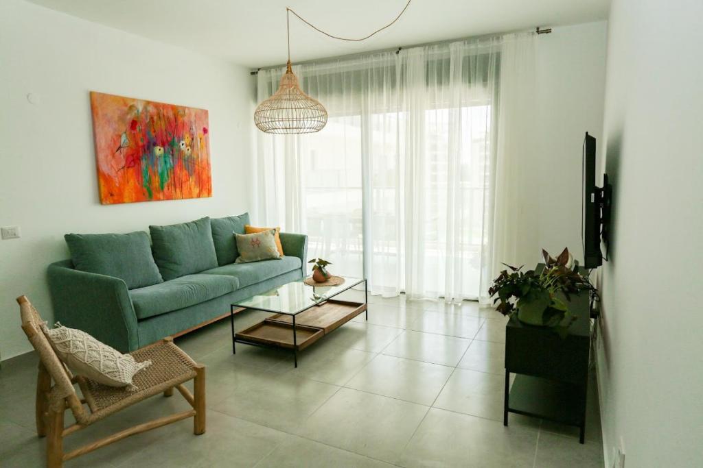 sala de estar con sofá azul y mesa en פנינה באכזיב- מול הים- achzivacation en Nahariyya