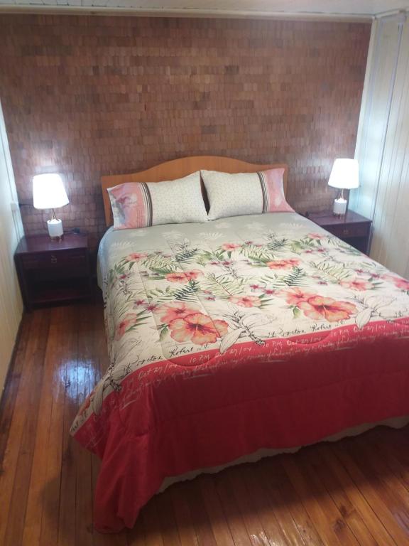 a bed in a bedroom with two lamps on tables at Refugio Insular in Castro