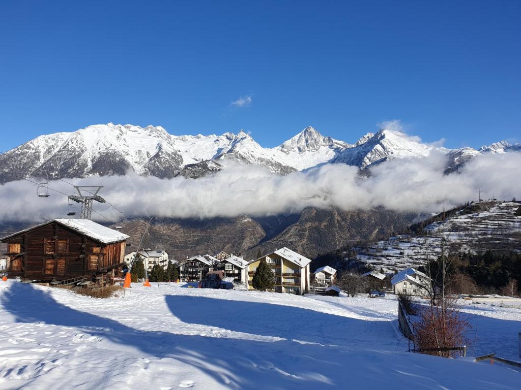 śnieżnobiałej góry z domkiem narciarskim i wyciągiem narciarskim w obiekcie Appartement Alpenperle w mieście Unterbäch