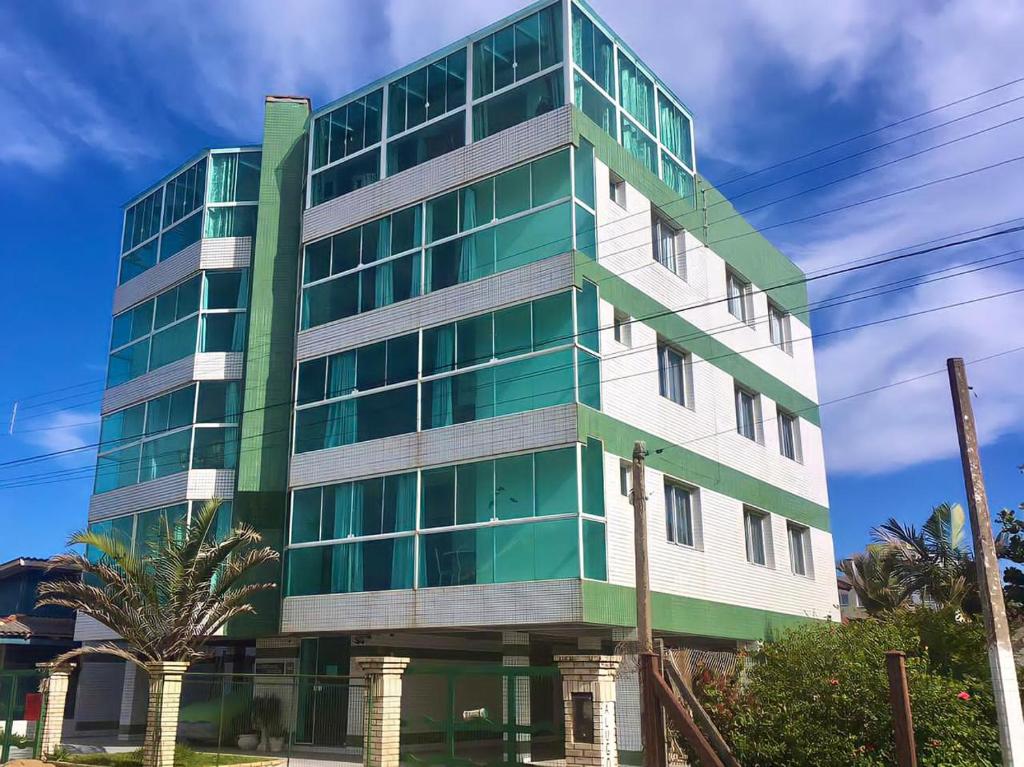 un edificio alto verde y blanco con una palmera en Tropical Tramandaí, en Tramandaí