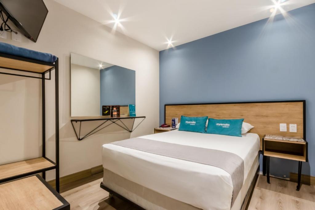 a bedroom with a large white bed with blue pillows at Ayenda Continental Mexicano in Mexico City