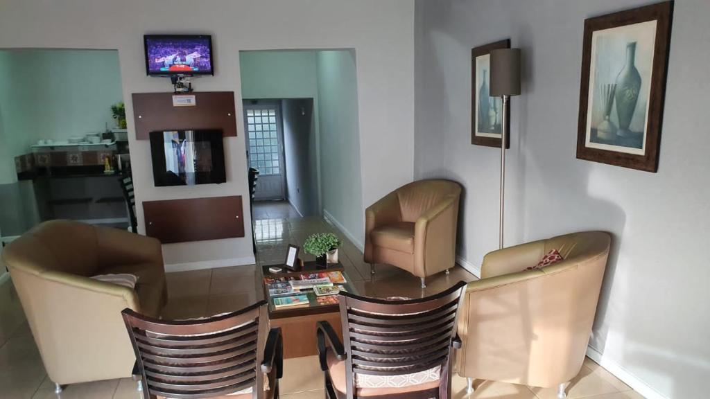 a living room with chairs and a table and a television at Hotel Apiai in Apiaí