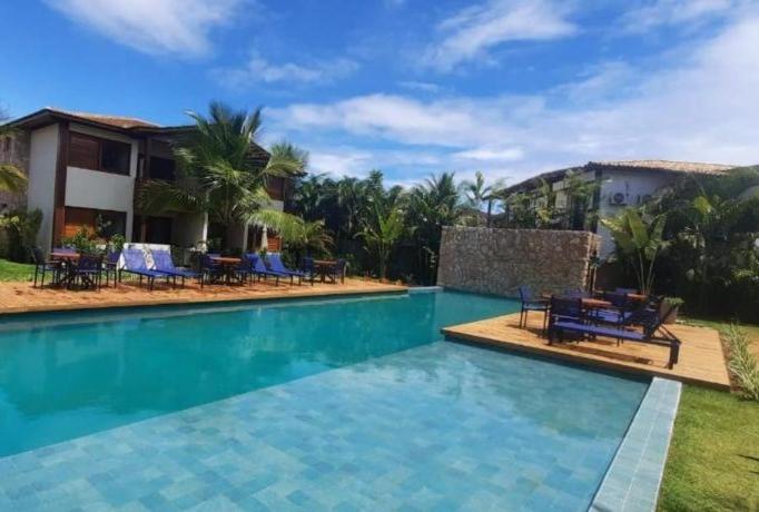 una piscina con sillas y una casa en Apartamento luxo Barra Grande Península de Maraú, en Maraú