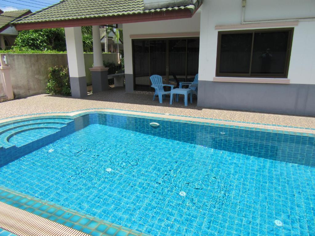 une grande piscine bleue en face d'une maison dans l'établissement Maks Villa, à Na Jomtien