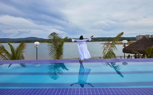 a woman standing on the edge of a swimming pool at Apartamento Resort do Lago in Caldas Novas
