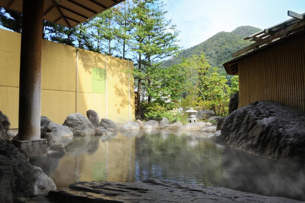 a stream of water next to a building and rocks at Shiobara Onsen Yashio Lodge in Nasushiobara
