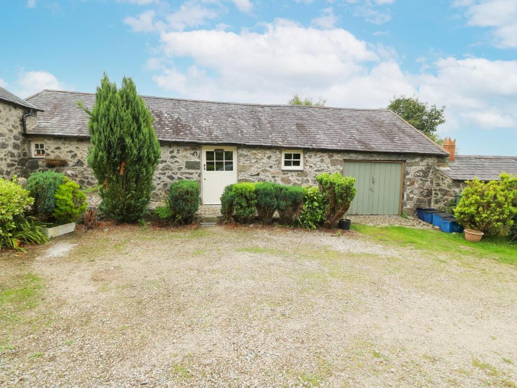 an old stone house with a driveway in front of it at Nant Bach in Pwllheli