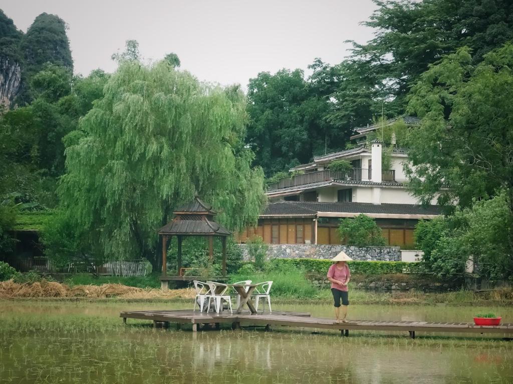 a woman standing on a dock next to a lake at The Apsara Lodge in Yangshuo