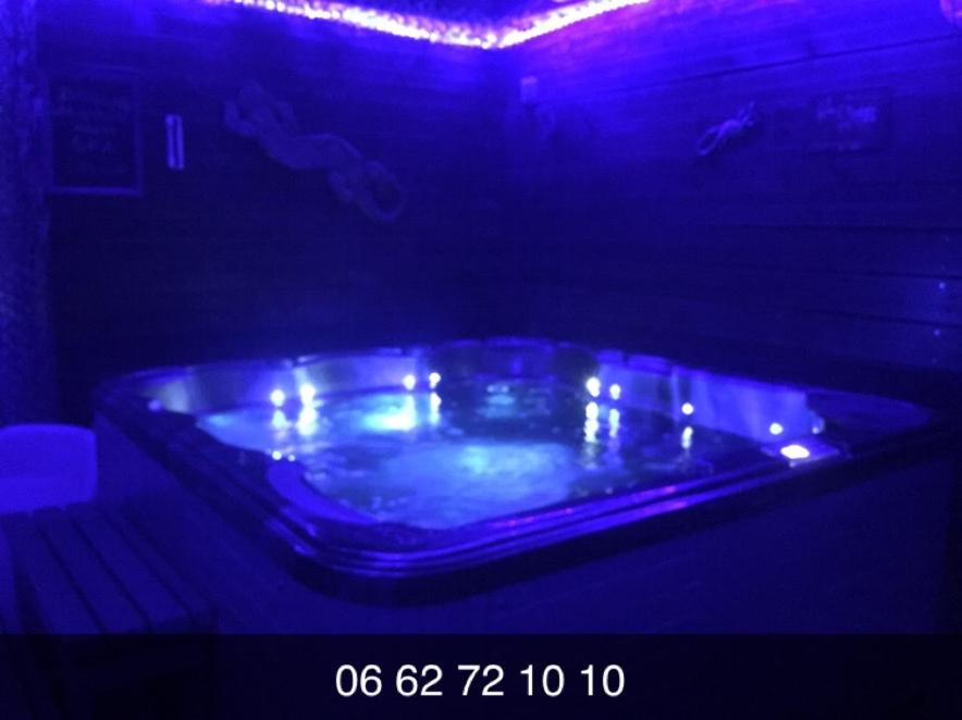 a blue tub in a dark room with lights at Séjour avec SPA **** sous le soleil ou sous les étoiles in Vauvert