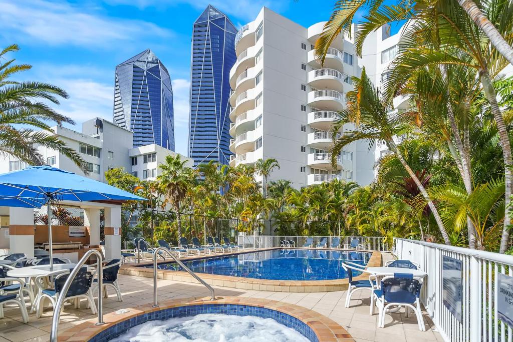 a swimming pool with tables and chairs and buildings at Surf Parade Resort in Gold Coast