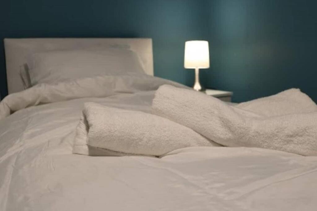uma cama com lençóis e almofadas brancos e um candeeiro em LARGE 12 Guests 5 Bedroom House in Birmingham City Centre em Birmingham