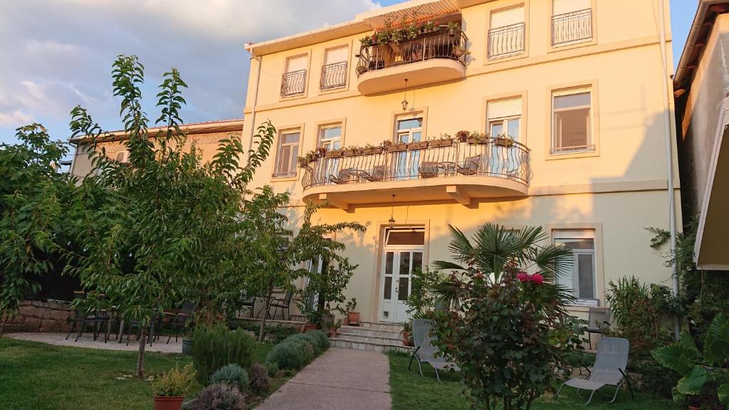 a large yellow building with a balcony on it at Aurelia Rooms in Mostar