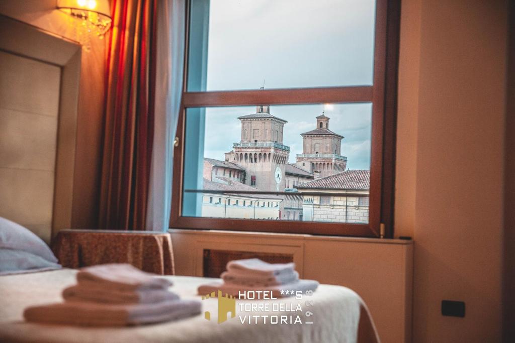 a room with a window with a view of a building at Hotel Torre della Vittoria 1928 in Ferrara