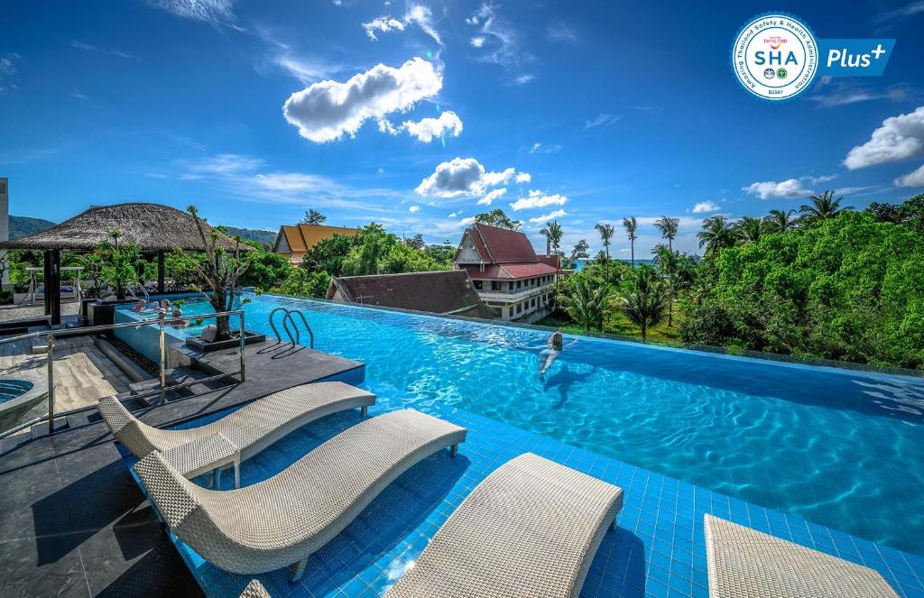 ein Pool mit Stühlen und eine Person im Wasser in der Unterkunft Andaman Beach Suites Hotel - SHA Extra Plus in Patong Beach