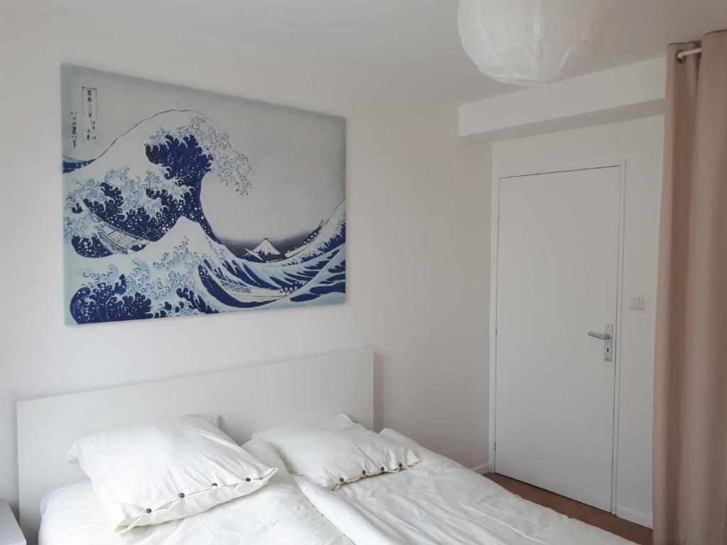 ein Schlafzimmer mit einem weißen Bett und einem Gemälde an der Wand in der Unterkunft Les Hauts de Marle in Marle-et-Behaine