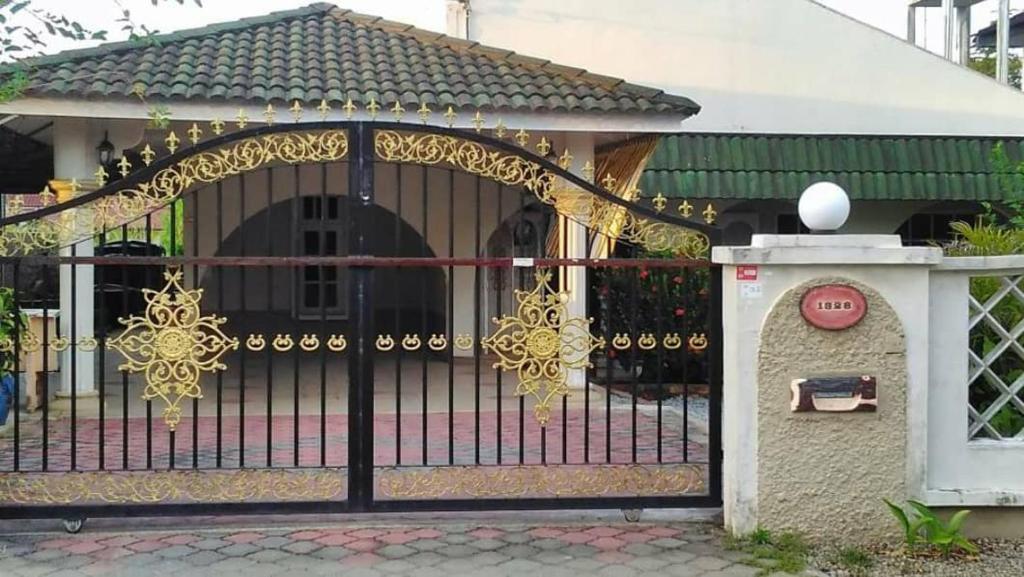 a gate to a house with a dog behind it at AbgZul Homestay in Kota Bharu