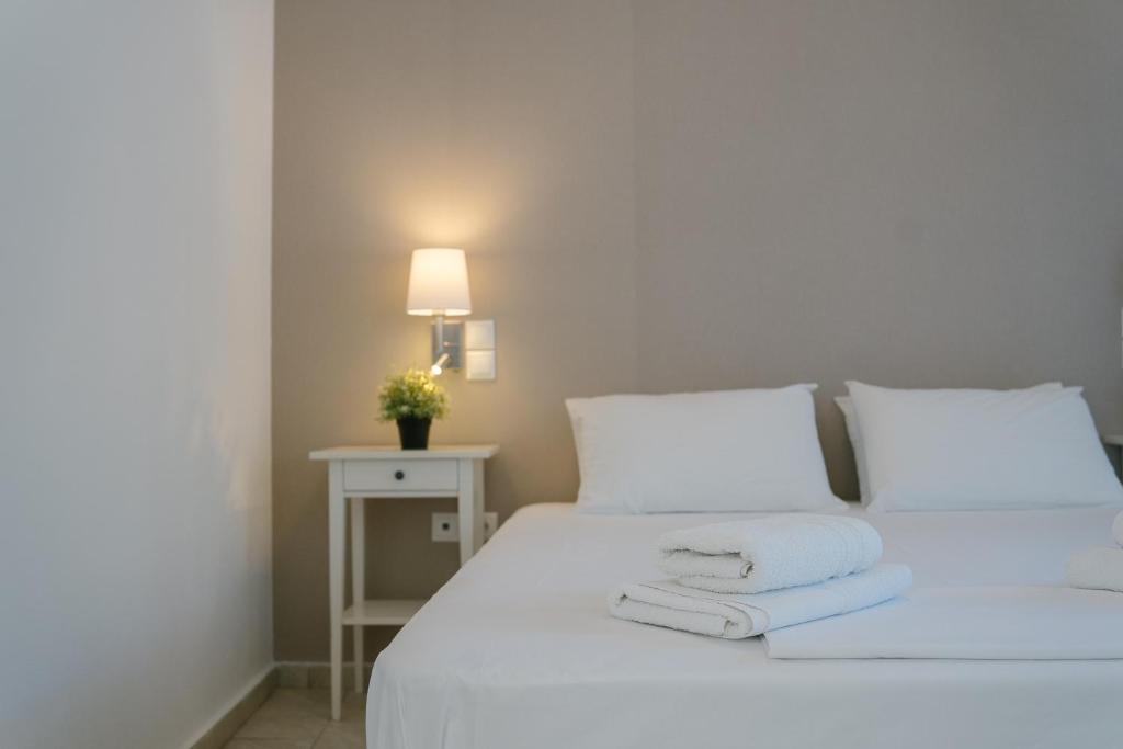 a white bed with white pillows and a table with a lamp at Indigo Studios in Livadi