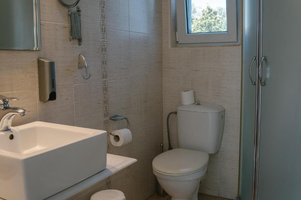 a bathroom with a toilet and a sink and a window at Indigo Studios in Livadi