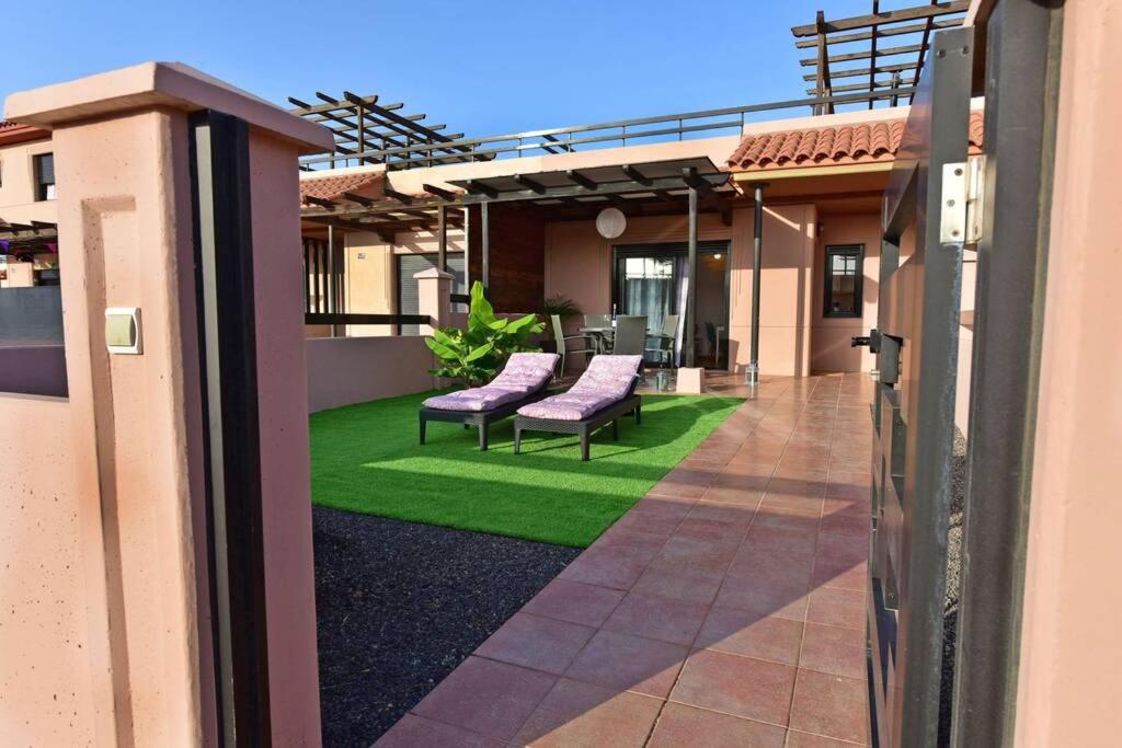 una casa con patio con césped verde y sillas moradas en Casa Platanera!!, en Lajares