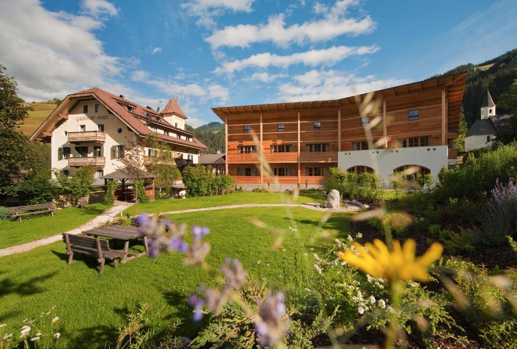 un edificio con cortile con panchina e fiori di Hotel Ostaria Posta a San Martino in Badia
