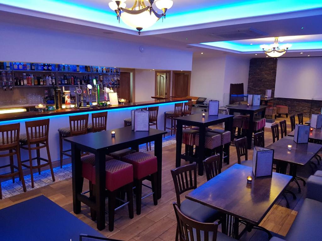 a restaurant with tables and chairs and a bar at Caisleain Oir Hotel in Annagry