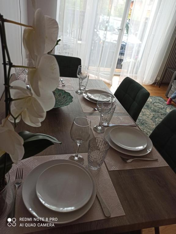 a wooden table with plates and wine glasses on it at NEW BIG LOFT APARTMENTS JURMALA with FREE SECURED PARKING in Jūrmala