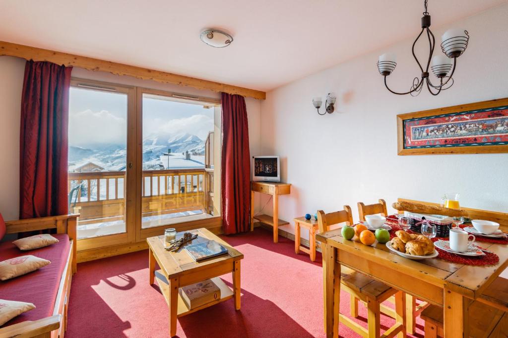 ein Wohnzimmer mit einem Tisch und ein Esszimmer mit einem Fenster in der Unterkunft travelski home select - Résidence L'Ecrin des Sybelles 4 stars by Travelski in La Toussuire