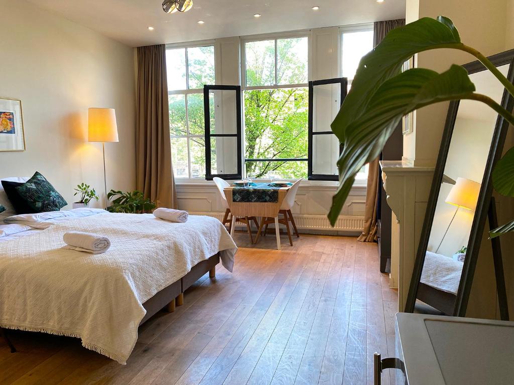 una camera con letto, tavolo e finestre di The Canalview Retreat ad Amsterdam