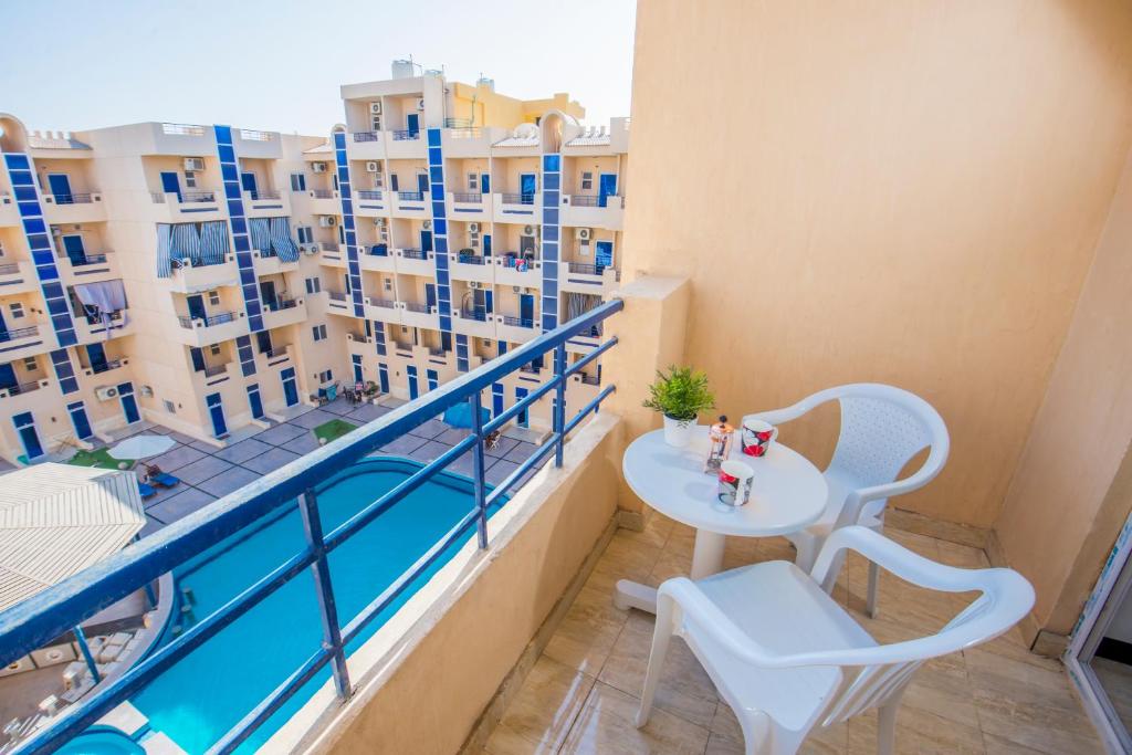 a balcony with a table and chairs and a view of buildings at Pool View Near El Gouna With Top Floor Balcony & Kitchen - 2 x Large Pools - European Standards - Tiba Resort C34 in Hurghada