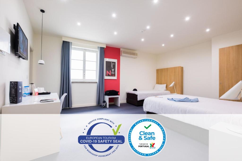 een hotelkamer met 2 bedden en een bord met schoon en veilig bij Stay Hotel Évora Centro in Évora
