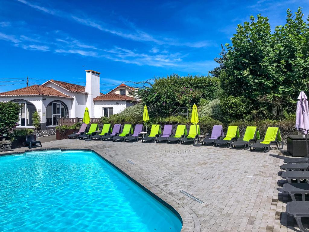 a swimming pool with chaise lounges and chairs at Quinta De Santana in Rabo de Peixe