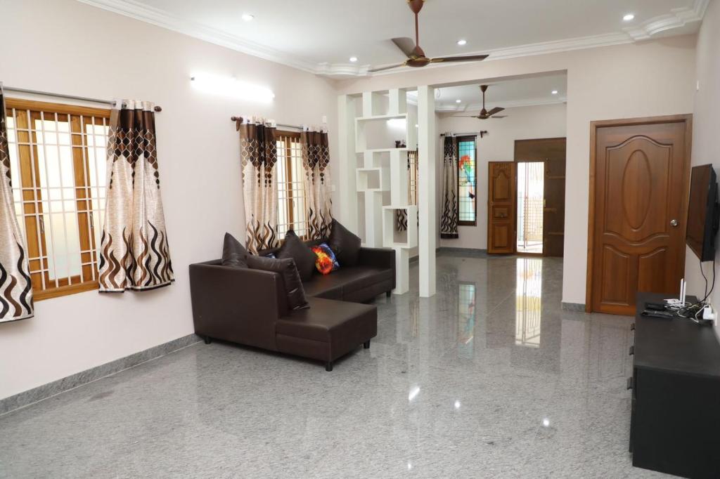 Sala de estar con 2 sofás y TV en Selvi Villa en Pondicherry